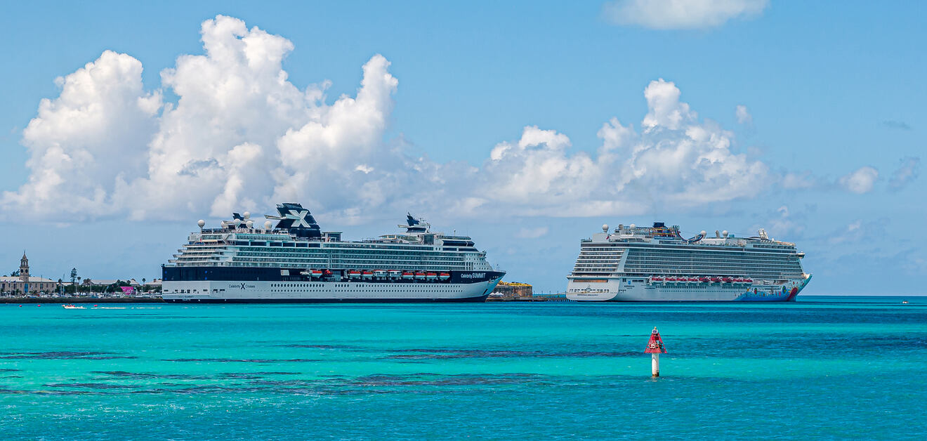Two large cruise ships docked in a vibrant turquoise sea under a partly cloudy sky.