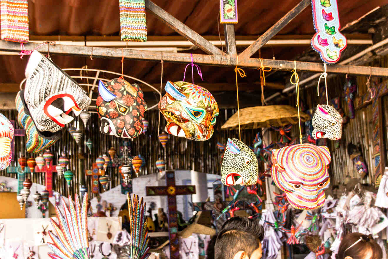 Colorful handcrafted masks and decorations hang in a market stall, displaying intricate patterns and designs.