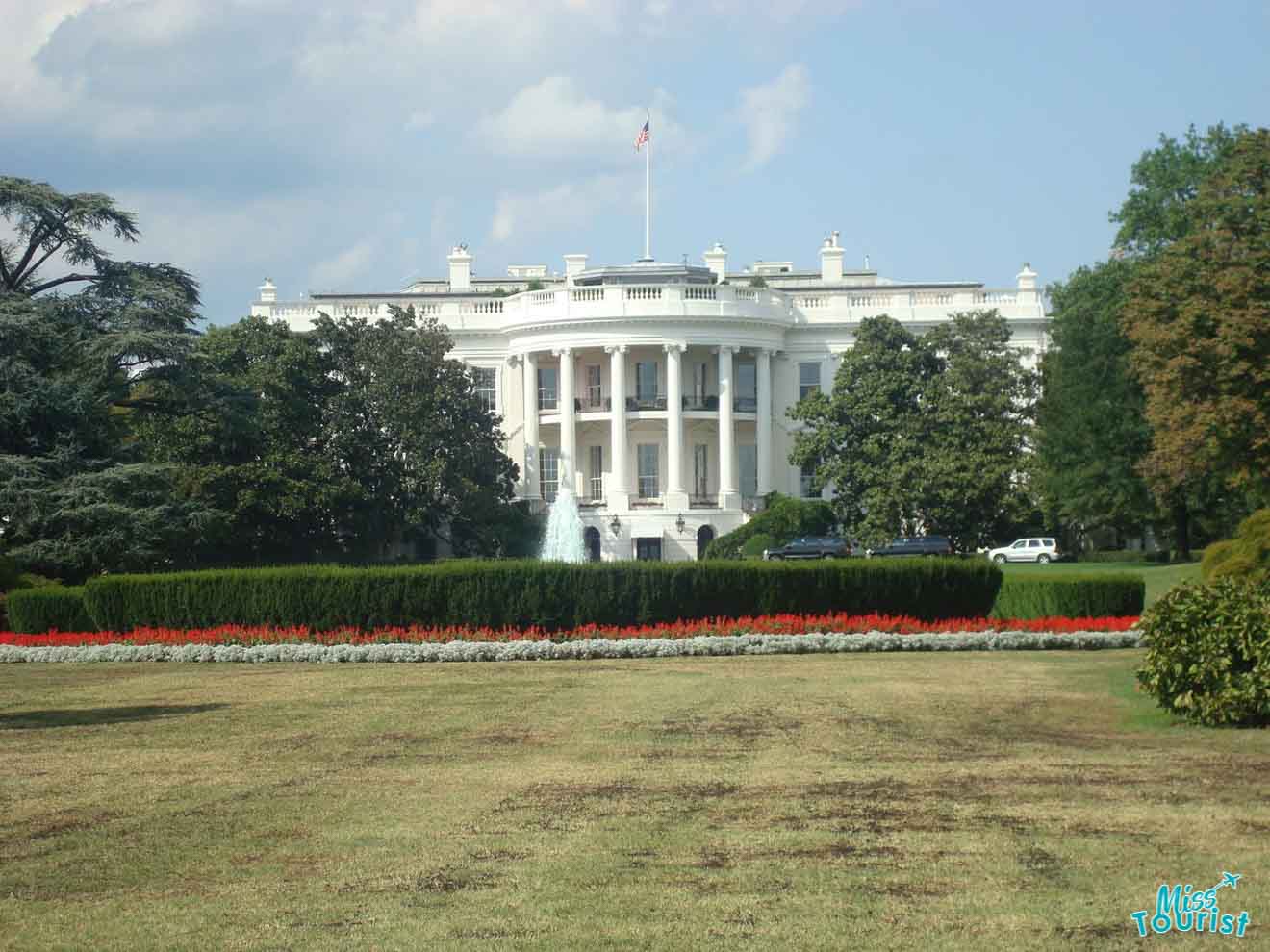 The White House in Washington D.C., viewed from the front lawn, displaying the iconic neoclassical facade with its stately columns and lush surrounding gardens.
