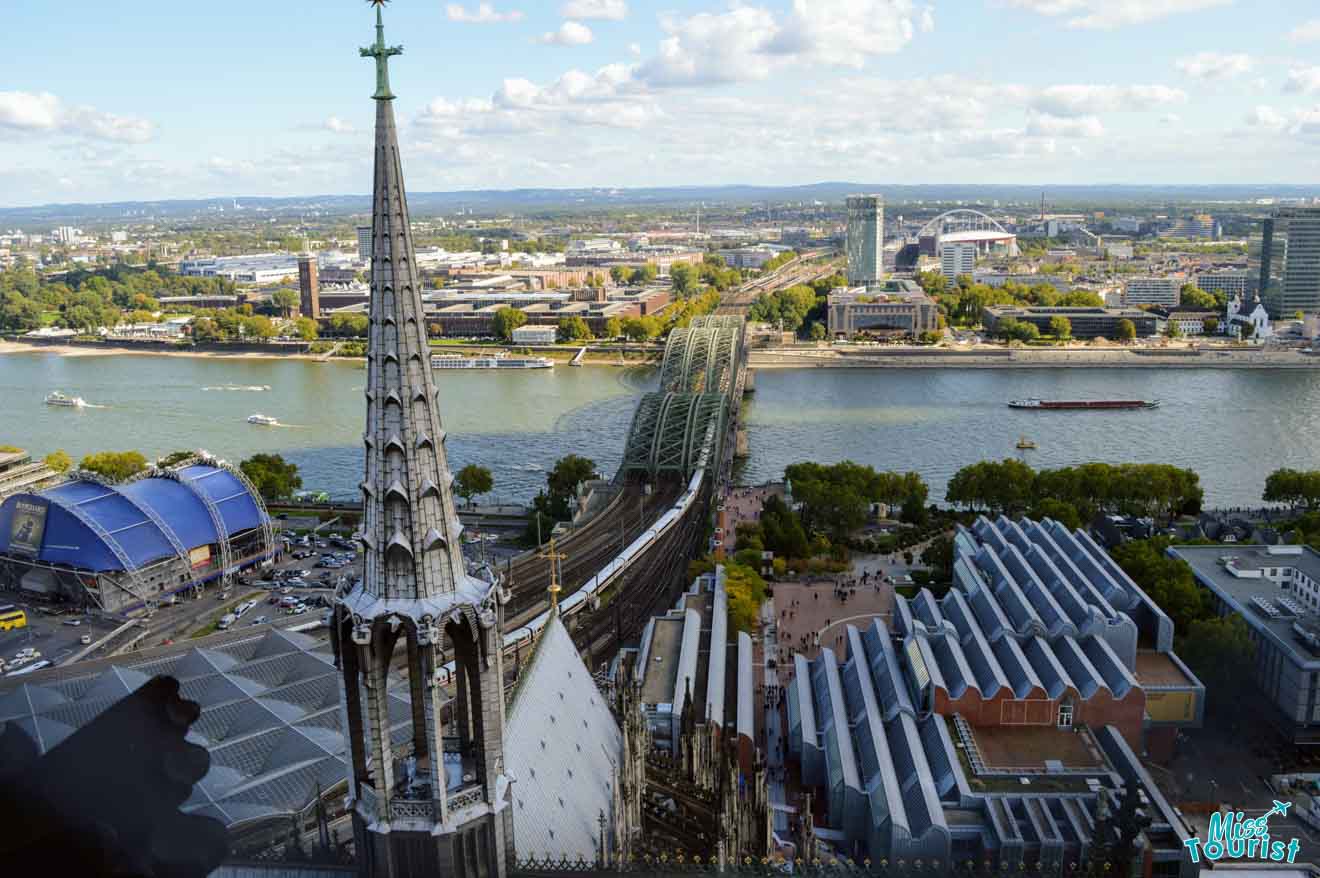 An aerial view of Cologne from the cathedral, overlooking the Rhine River, Hohenzollern Bridge, and the modern architecture of the Museum Ludwig.