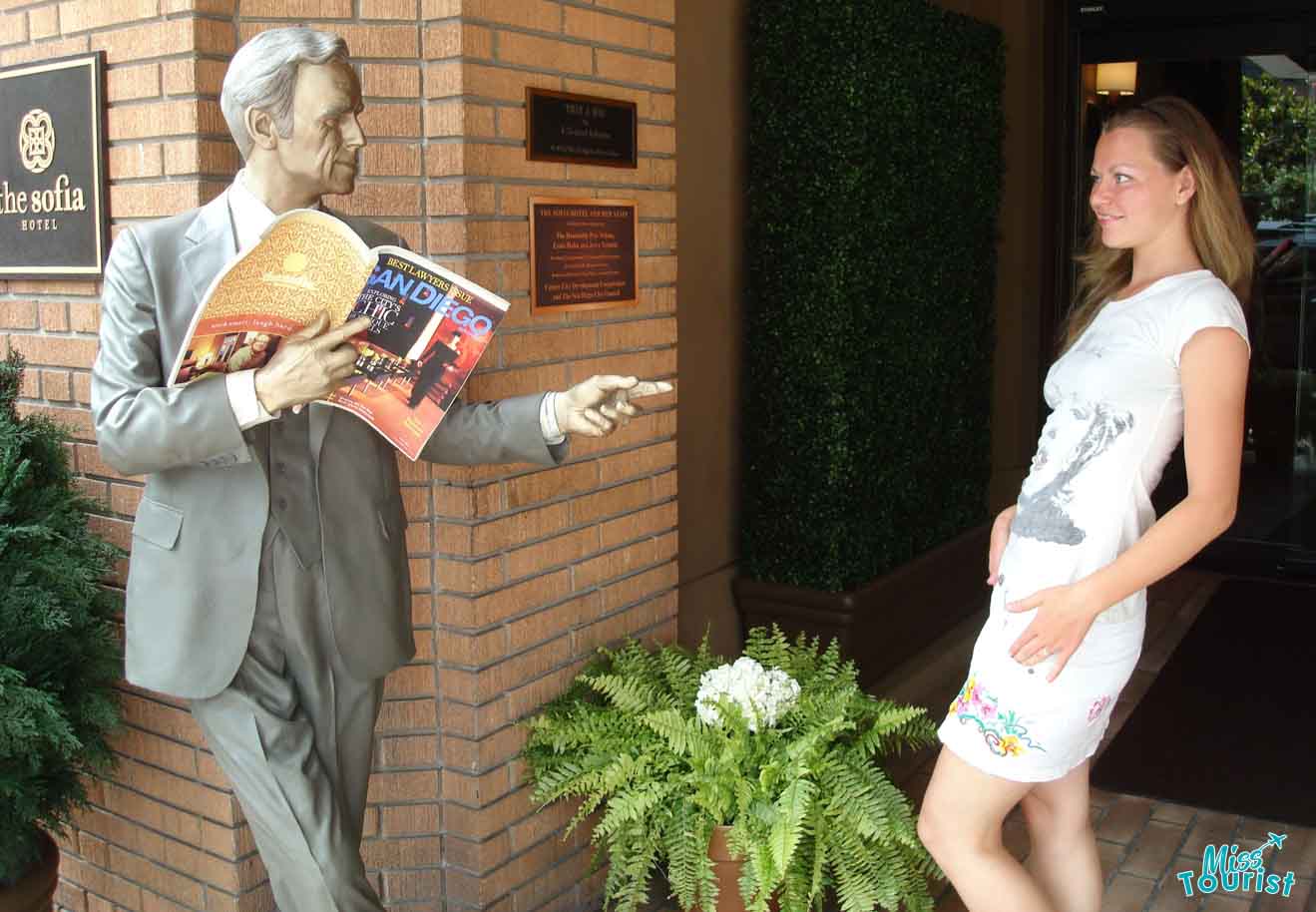a girl next to a monument of a man holding a magazine