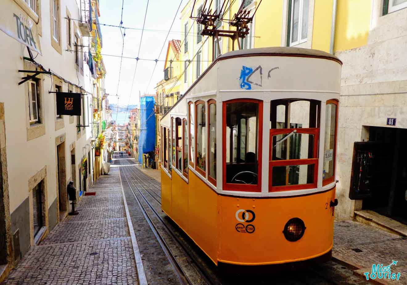 Classic Lisbon yellow tram navigating a narrow street, lined with traditional buildings, under the clear blue sky