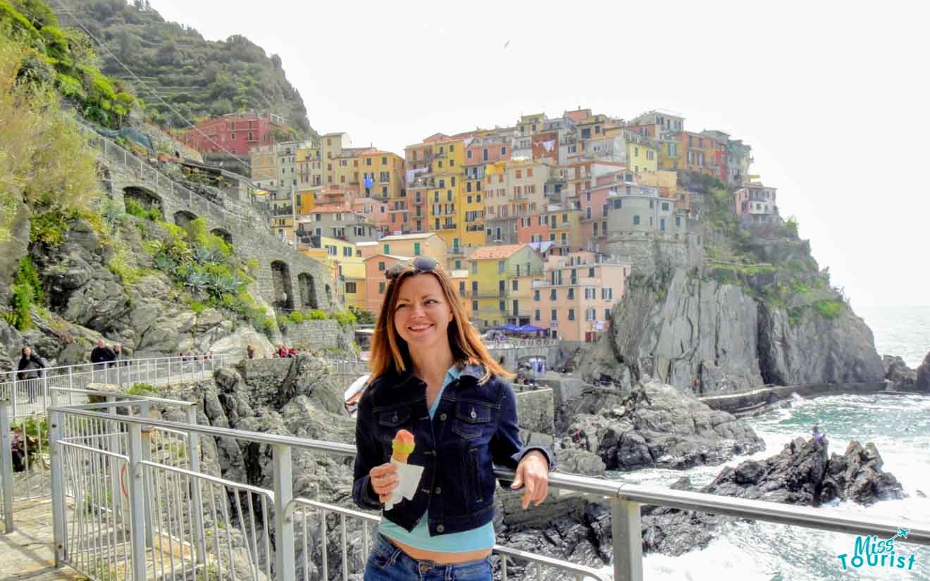 The writer of the post enjoying gelato in front of the vibrant and picturesque cliffside village of Manarola, Cinque Terre, embodying the joy of Italian travel