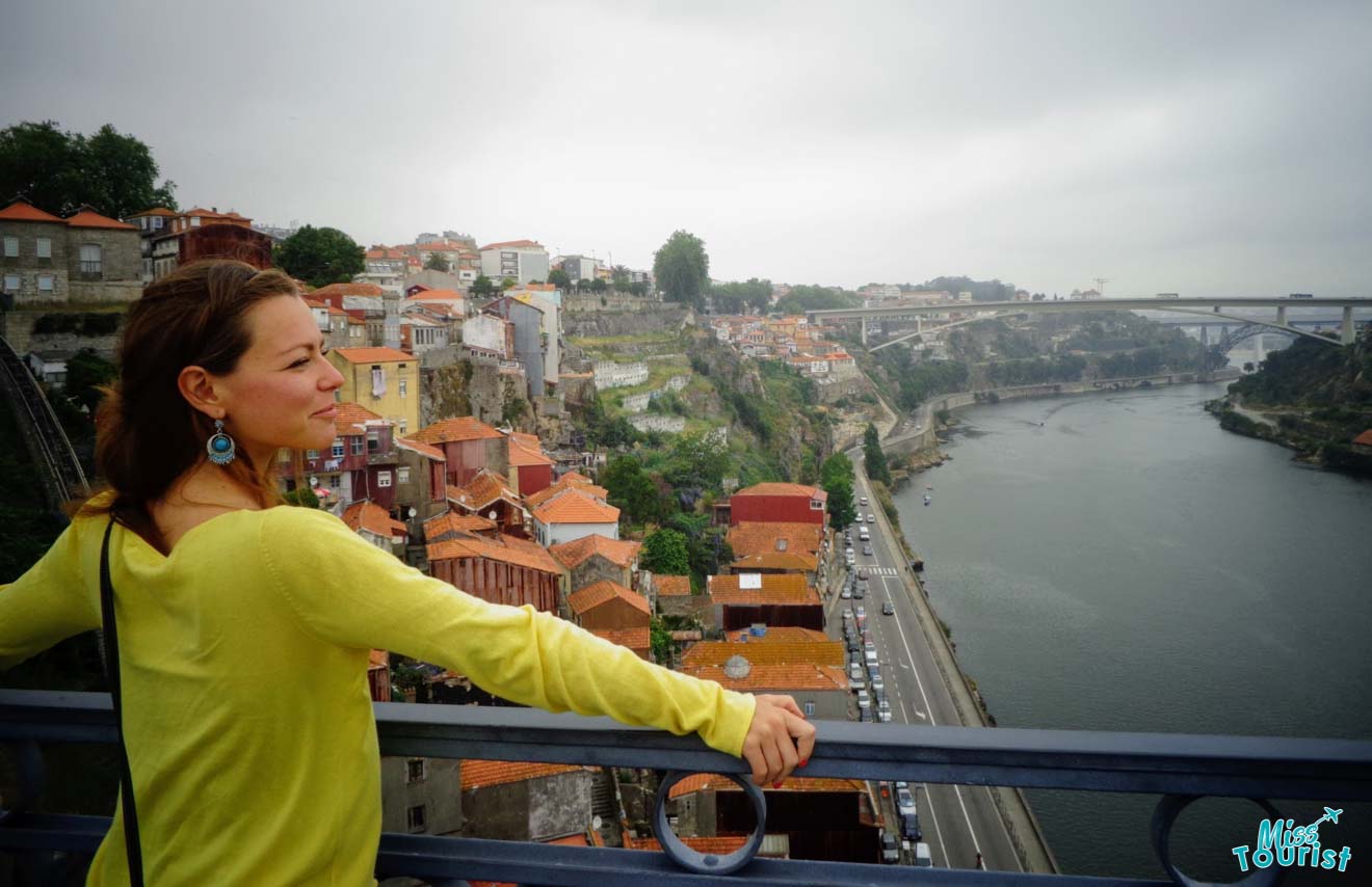 The writer of the post gazes out over the historic Ribeira district of Porto, with the Douro River and Dom Luís I Bridge in the background on an overcast day.