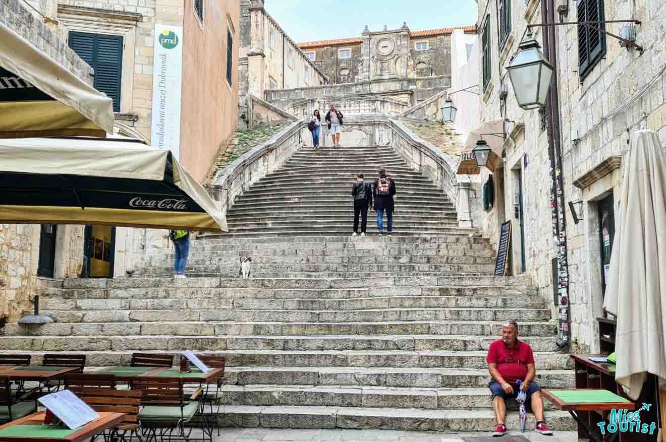 Historic baroque Jesuit Stairs in Dubrovnik, lined with cafe tables and frequented by tourists