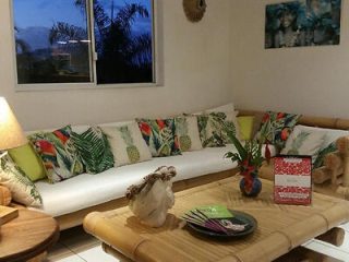 A comfortable seating area with a white couch, tropical-themed pillows, and a bamboo coffee table.