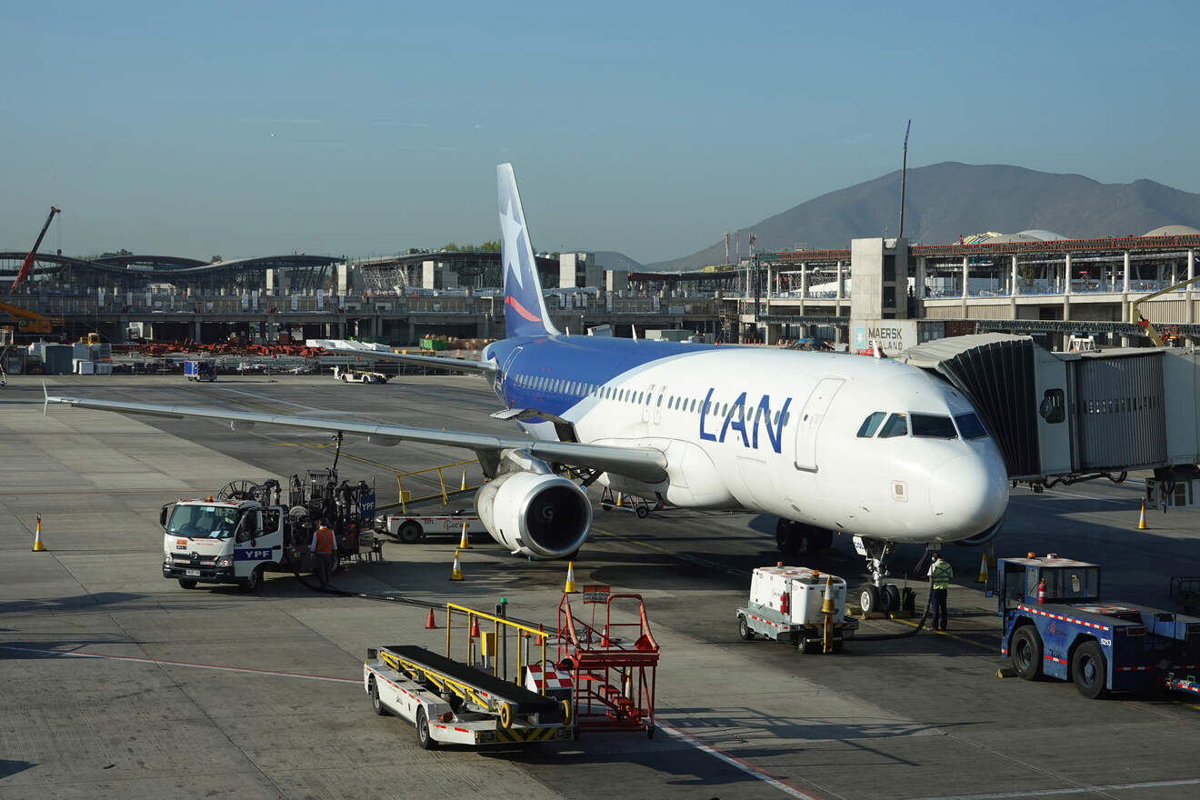 A LAN Airlines plane being serviced at Santiago International Airport with surrounding terminal construction.