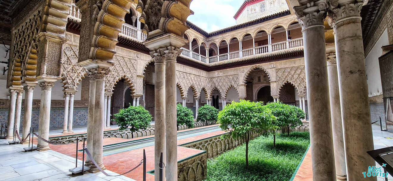 Serene courtyard of the Real Alcázar in Seville, displaying exquisite Mudéjar architecture with ornate arches, detailed carvings, and a lush garden, embodying the historical cross-cultural artistry of Spain