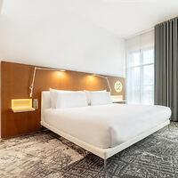 A modern hotel room with a king-size bed, wooden headboard, and soft lighting 