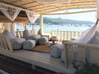 A beachside lounge area with comfortable seating and a view of the bay.