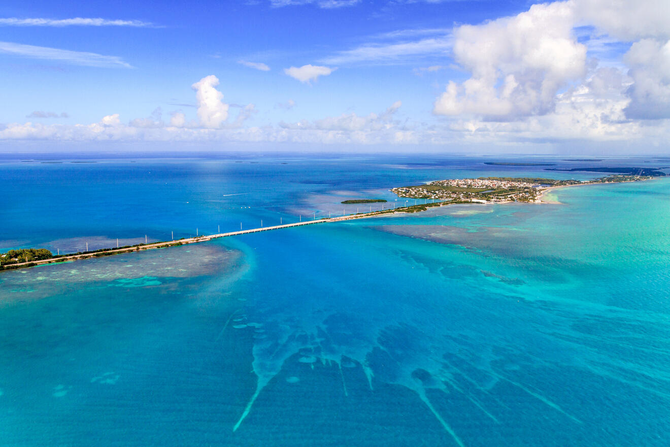 A long bridge stretching over vibrant blue waters, connecting small islands under a bright, clear sky in the Florida Keys