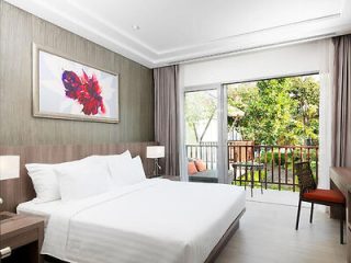 A bright, modern hotel room with a king-sized bed and a view of the garden.