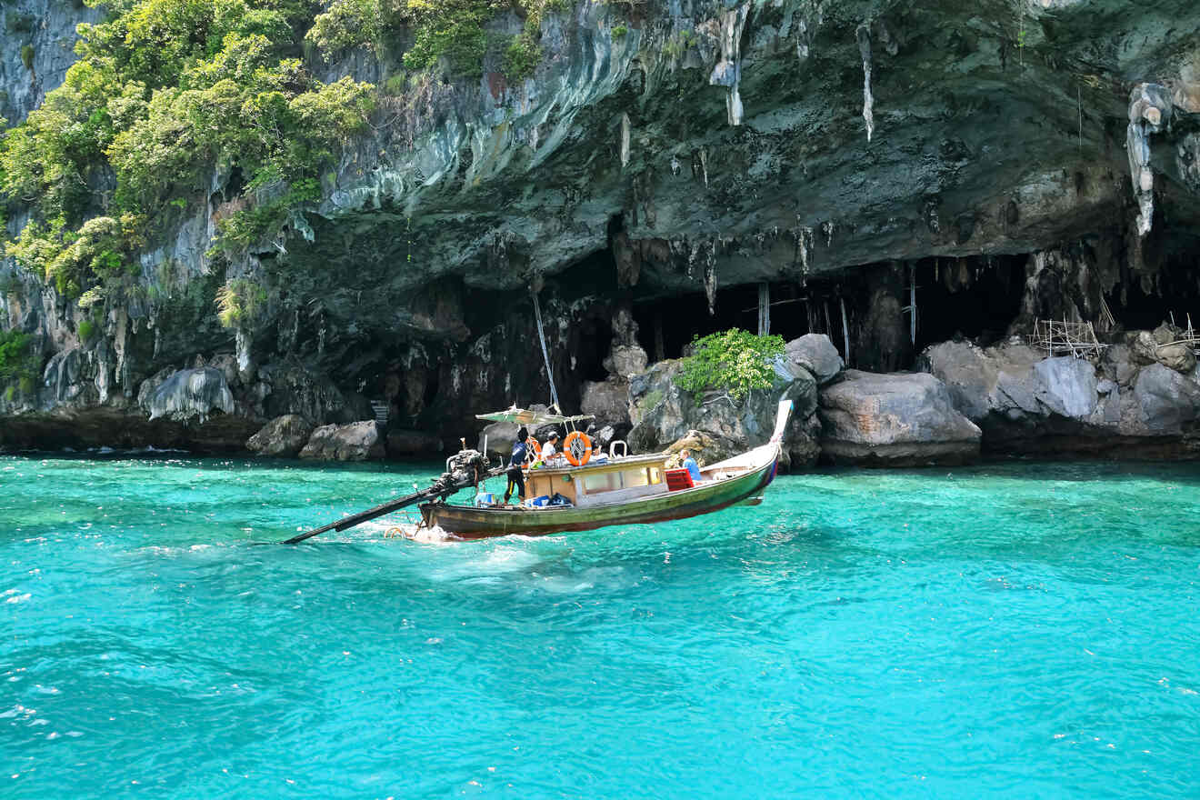 A small boat on crystal clear water near the entrance of a rocky cave.
