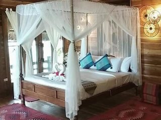 A luxurious bedroom with a canopy bed, sheer white curtains, and rustic wooden decor.