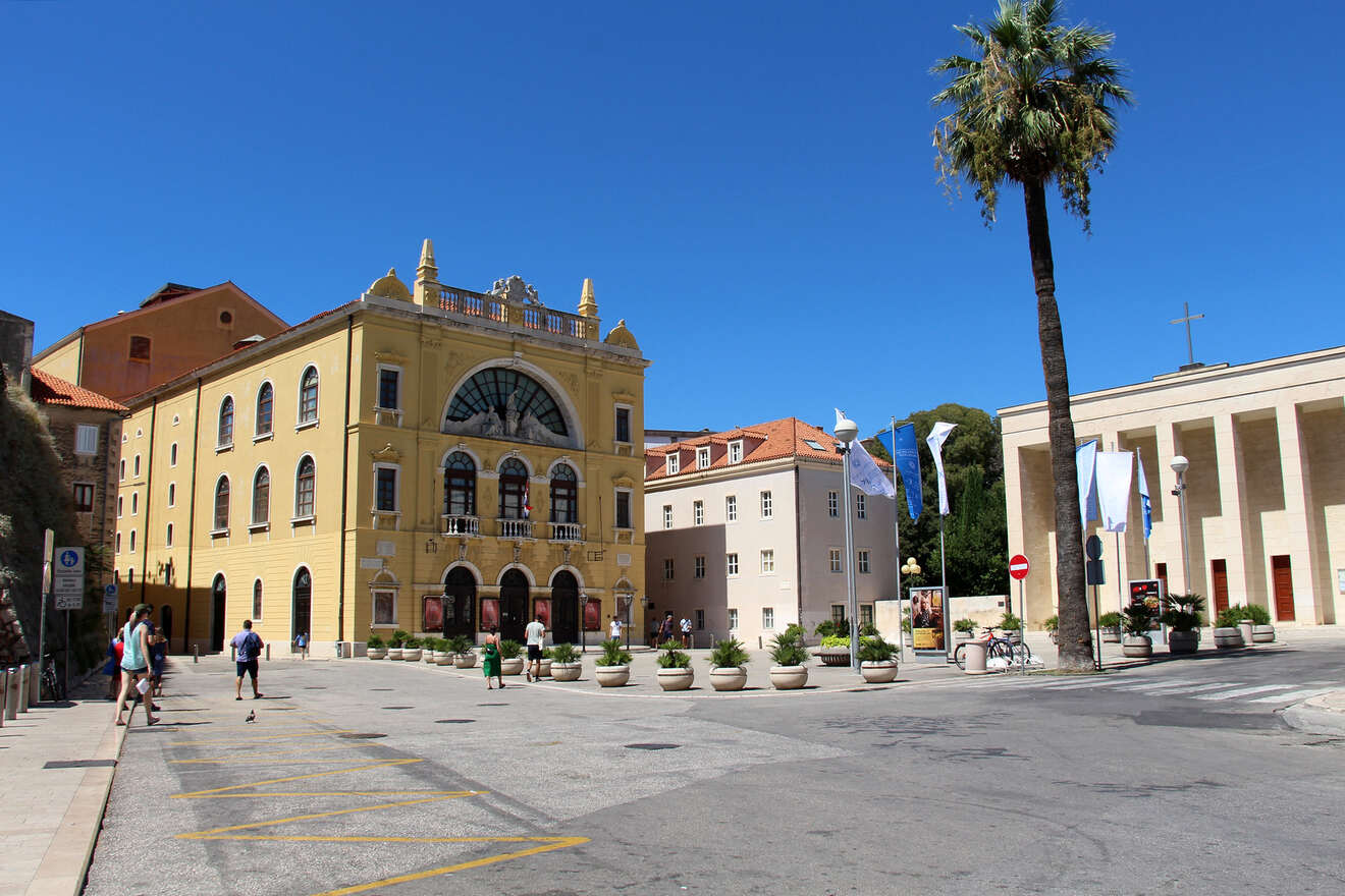A spacious square flanked by classical architecture and modern buildings, under a clear blue sky in Split, Croatia