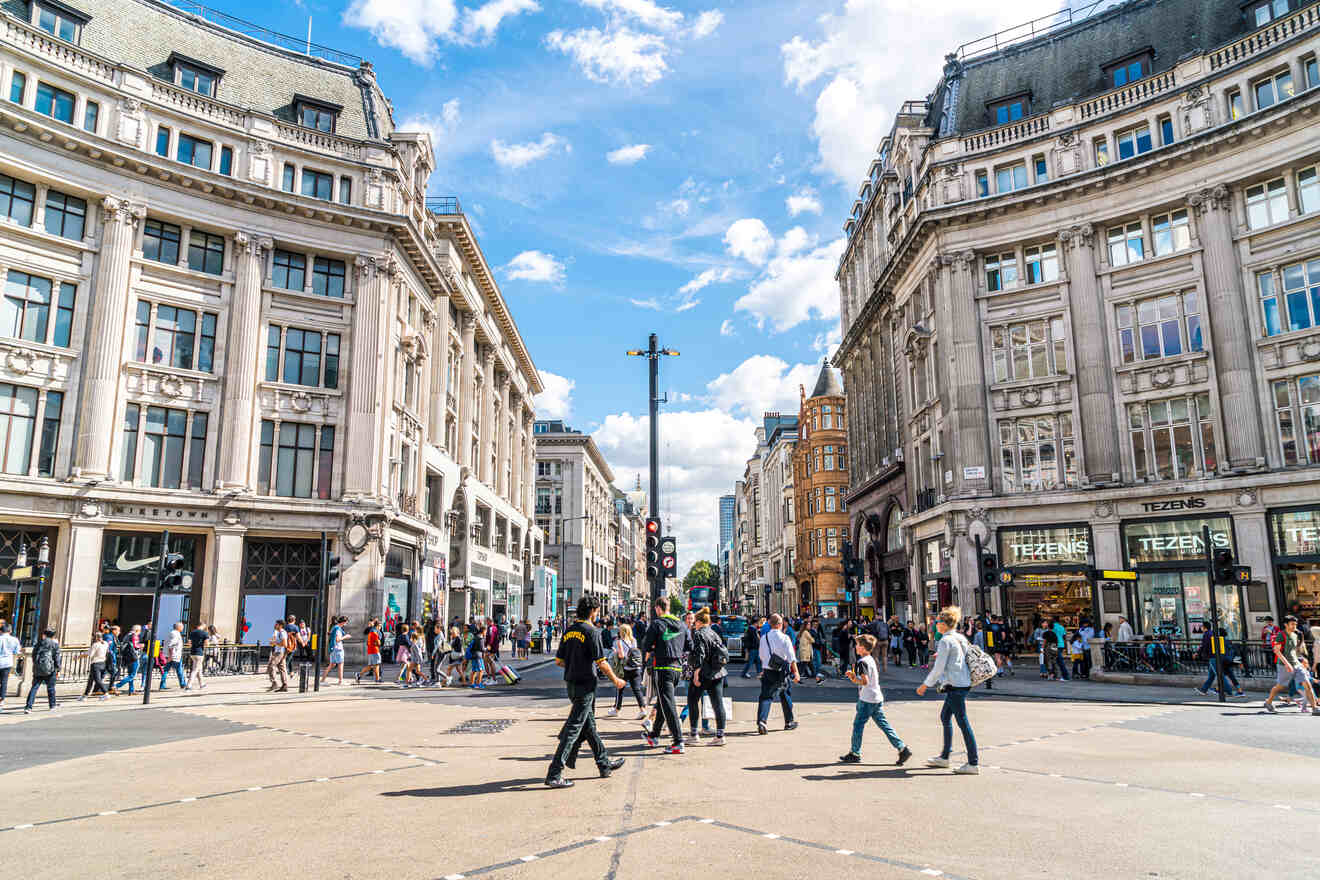 People walking at a busy intersection between historic buildings under a partly cloudy sky.