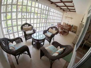 Spacious screened patio with rattan furniture set and cushions, overlooking a lush garden view