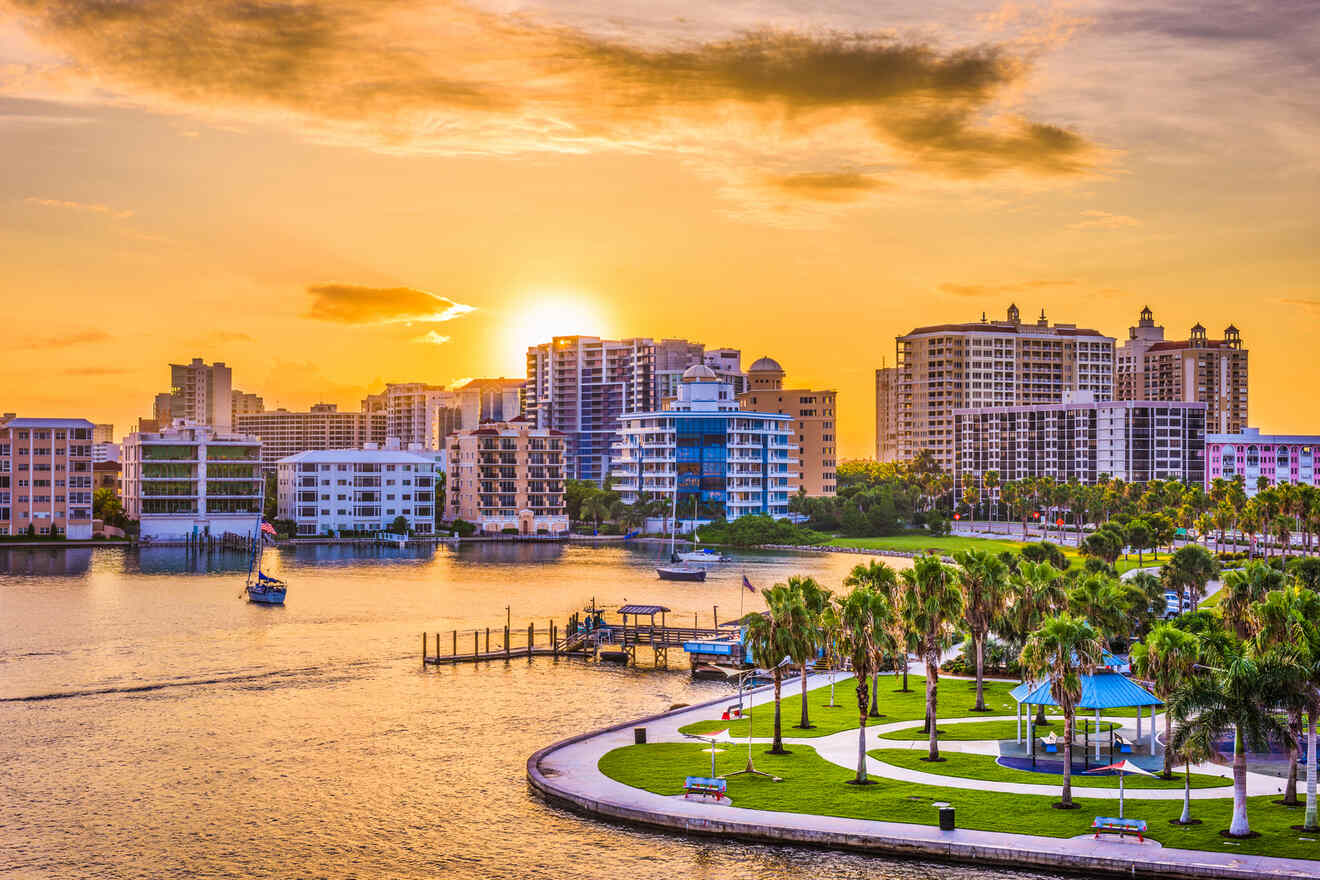 A beautiful sunset view of a coastal city with tall buildings, palm trees, and boats in the water, as the golden sun dips behind the skyline.