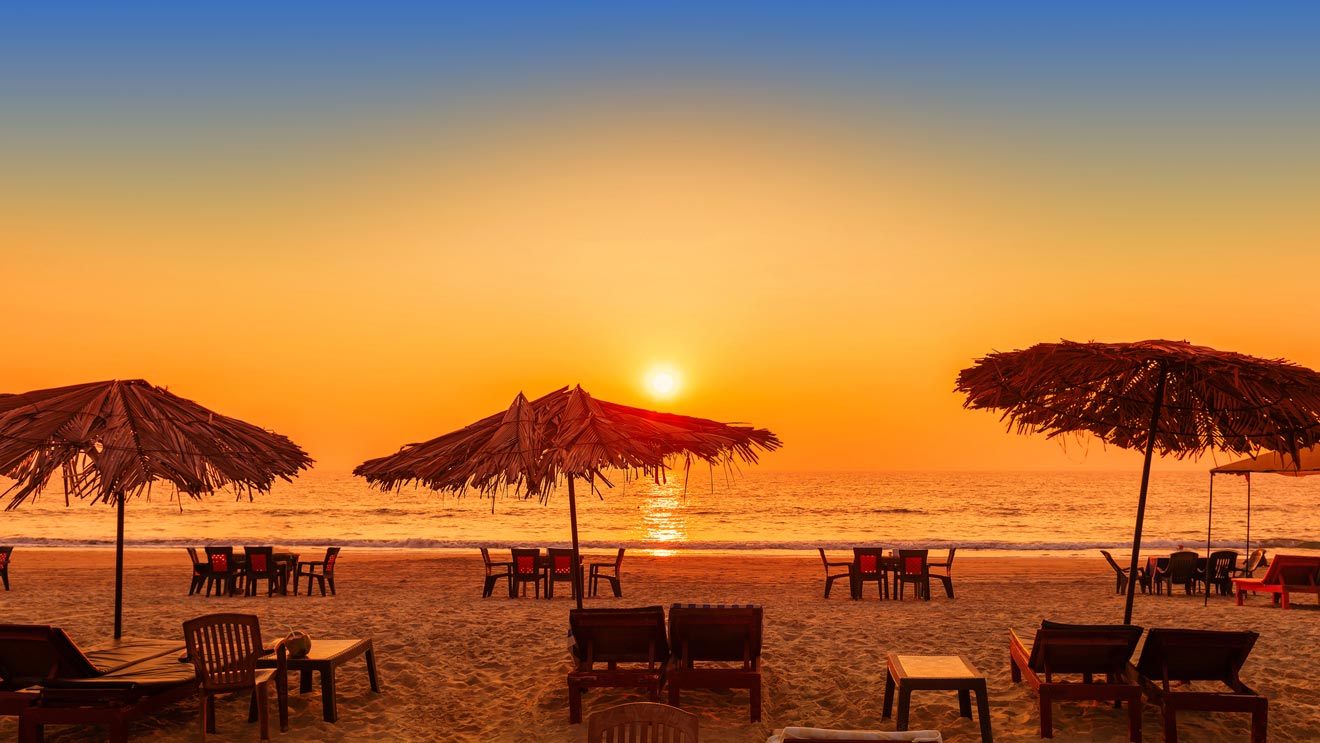 chairs and umbrellas on a beach at sunset