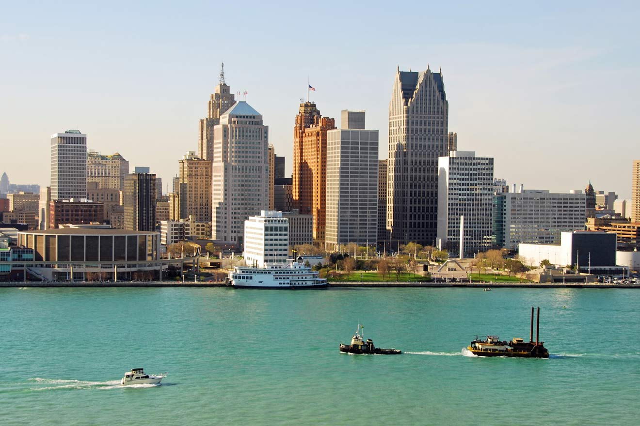 Detroit skyline with a variety of modern and historic buildings viewed across the blue waters of the Detroit River, with a ferry and tugboat in the foreground