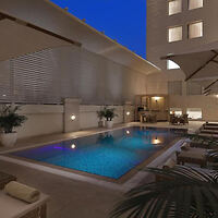 Elegant hotel pool area at night with loungers and ambient lighting.