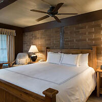 A cozy bedroom with a large bed, wooden headboard, and a ceiling fan.