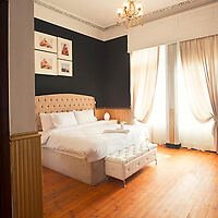 Cozy hotel room with a plush bed, wooden floor, and elegant curtains