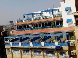 Exterior of a multi-level hotel with blue balconies and rooftop greenery.