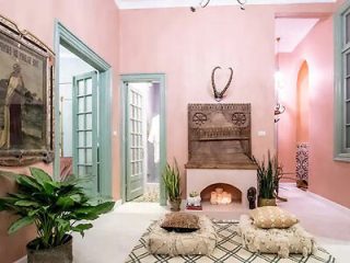 Stylish living room with a pink theme, plants, and a decorative fireplace.