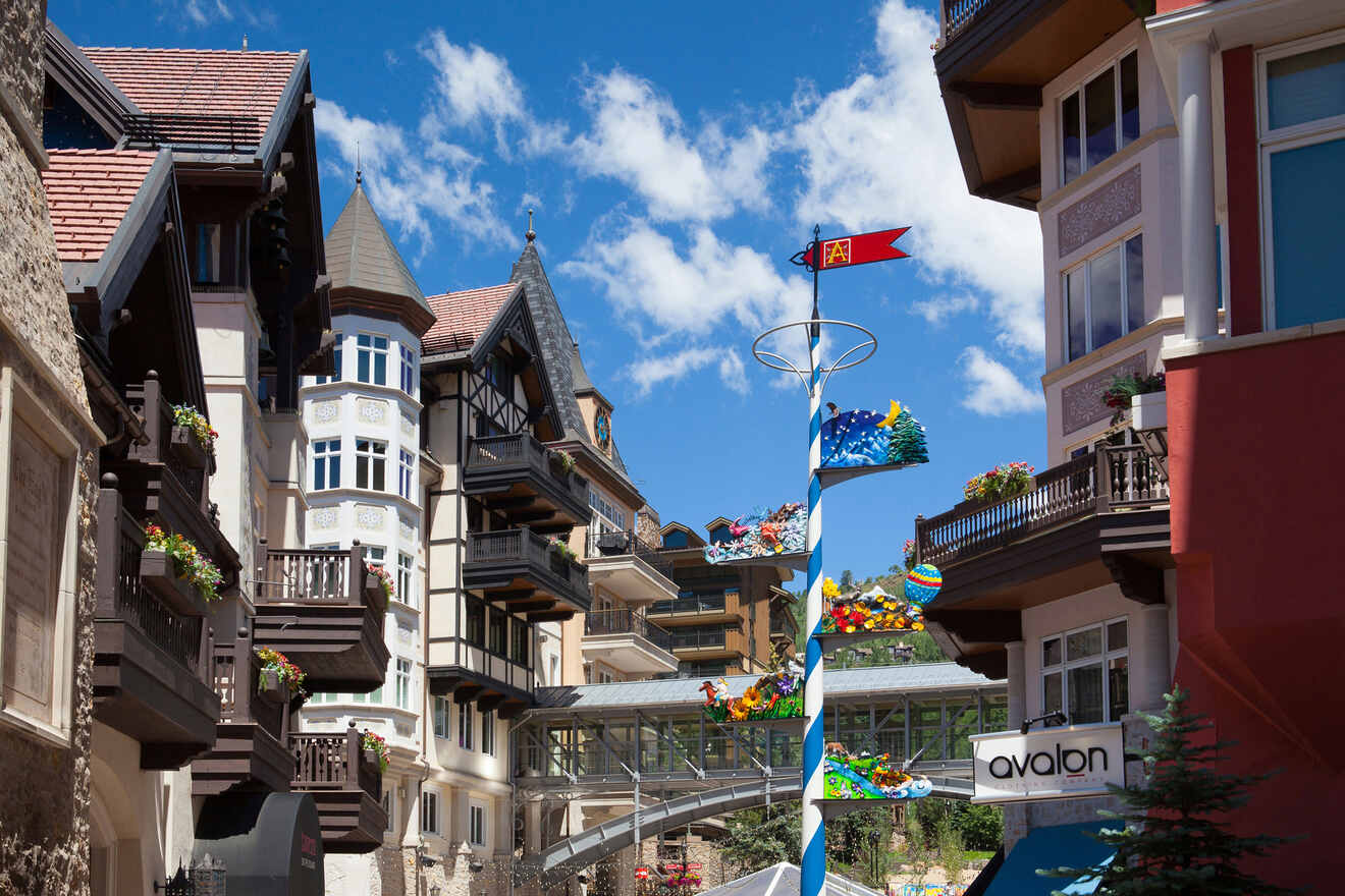 Quaint European-style village street in Lionshead Village with colorful buildings, decorative flags, and a clear blue sky