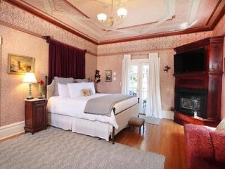 A luxurious bedroom with ornate wallpaper, a fireplace, and elegant furnishings.