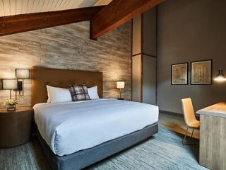 Contemporary hotel room with a large comfortable bed, wooden beam ceilings, and minimalist decor