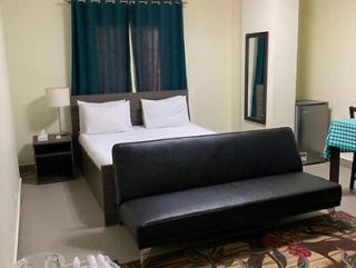 Simple hotel room with a double bed, black couch, and teal curtains