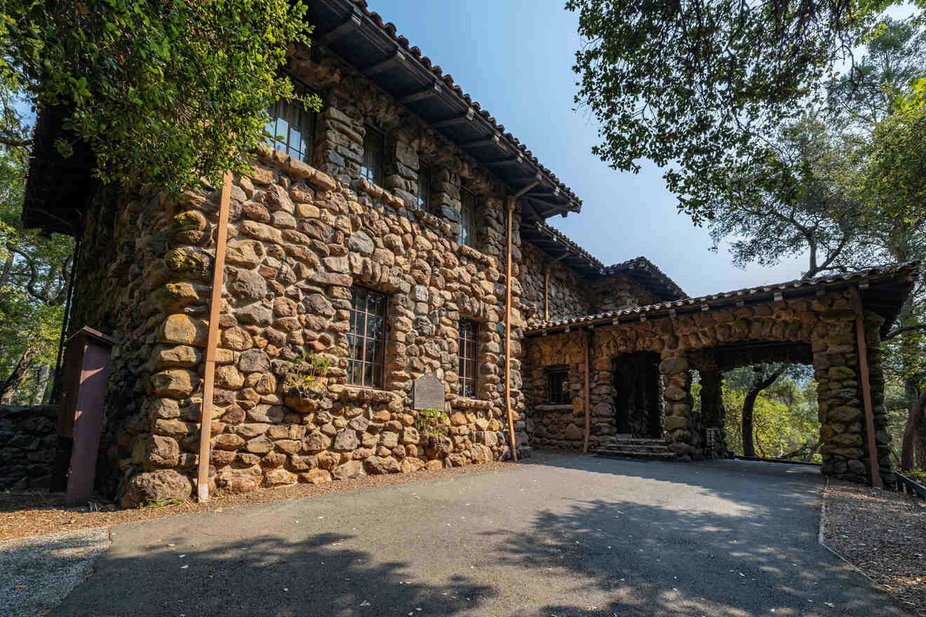 A rustic stone building with arched entrances and surrounded by trees.