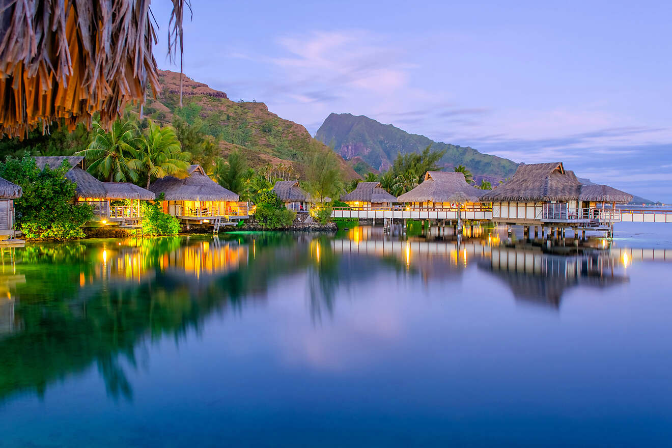 sunset in Bora Bora island, with overwater bungalows surrounded by palm trees