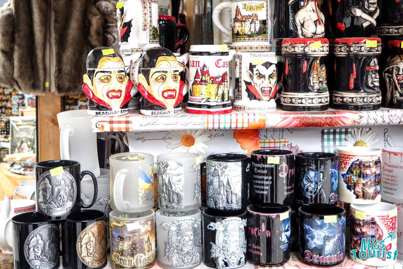 A display of various souvenir mugs featuring vampire themes and cityscapes, arranged on shelves in a shop.