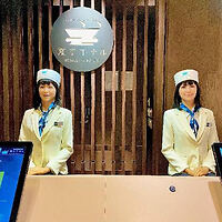 Hotel reception desk with two robots - staff members in uniform standing ready to assist guests, with the hotel's emblem in the background