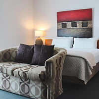 Modern hotel room with a patterned sofa, abstract wall art, and warm lighting creating an inviting atmosphere