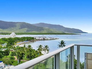 Breathtaking view from a balcony overlooking a serene bay, lush mountains, and a coastal resort landscape