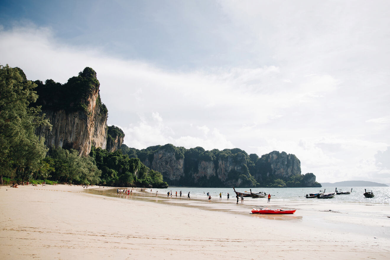 Breathtaking view of Railay Beach in Krabi, Thailand, featuring a wide stretch of sandy shore with tourists strolling and swimming