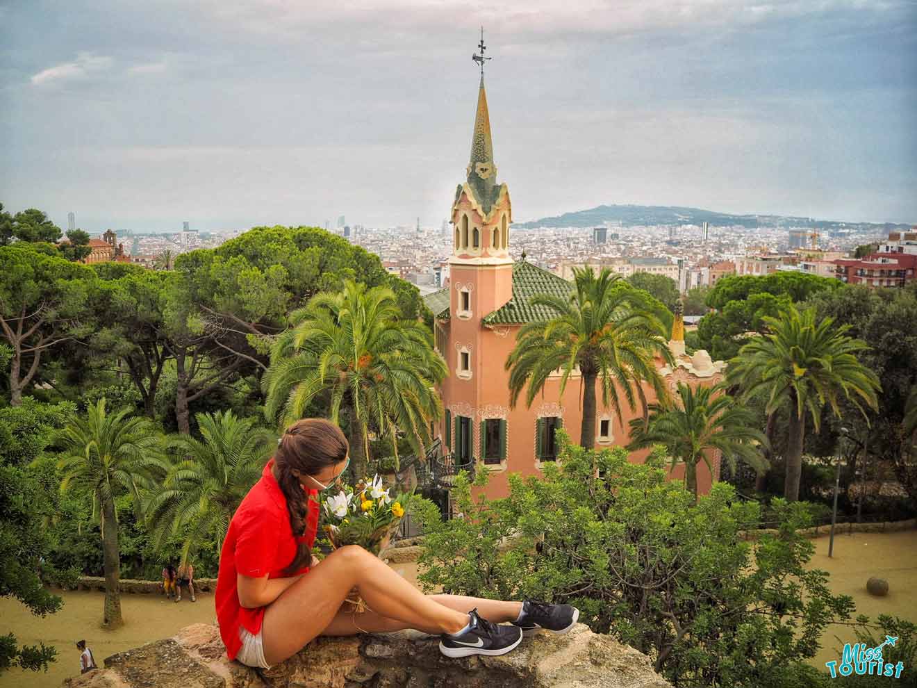 A woman sitting on a rock overlooking the city of barcelona.