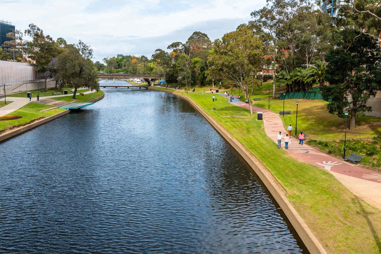 Parramatta Park with a winding river, pedestrian paths, and green lawns, bordered by a cityscape, suggestive of a tranquil area within a bustling city