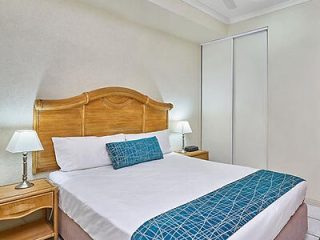 Neat hotel room with a wooden headboard, white bedding, and a geometric patterned runner across the bed