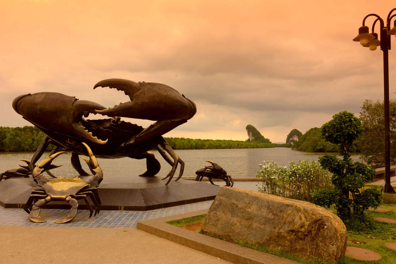 Dramatic sculpture of two crabs in combat, set against a moody sky at dusk, with a backdrop of a tranquil river and distinctive rock formations
