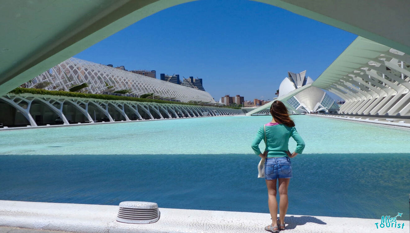 The writer of the post stands at the edge of a turquoise reflecting pool, admiring the futuristic white architecture of the City of Arts and Sciences complex under a clear blue sky