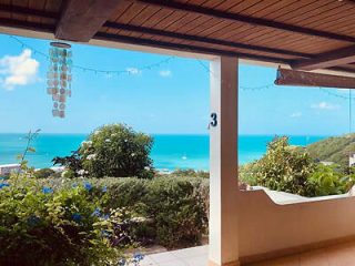 Cozy porch with a view of the ocean, featuring a bathtub and hanging wind chimes, perfect for a relaxing retreat