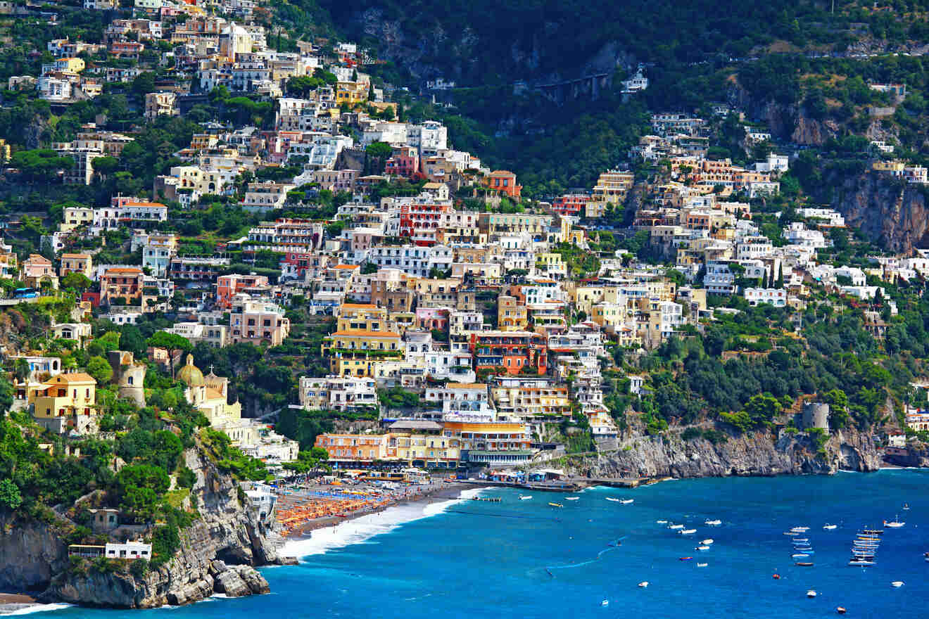 View of the colorful buildings and a beach with umbrellas in a bay in the town of Positano on the Amalfi coast, Italy.