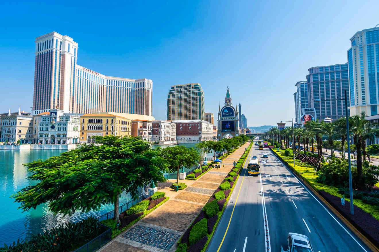 Wide boulevard with palm trees, luxurious resorts including The Venetian Macao, and a calm blue canal on a sunny day.