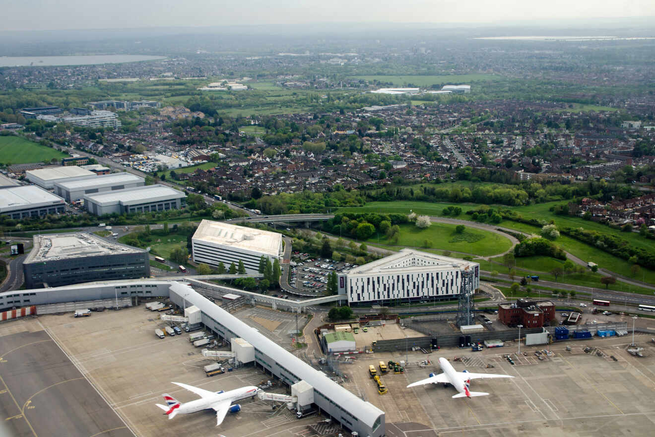 Overhead shot of airplanes at an airport terminal with a suburban backdrop