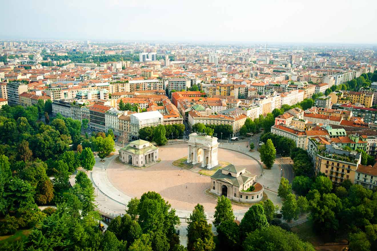 Panoramic view overlooking the expansive Sempione Park in Milan, featuring the prominent Arch of Peace (Arco della Pace) and a sprawling urban landscape